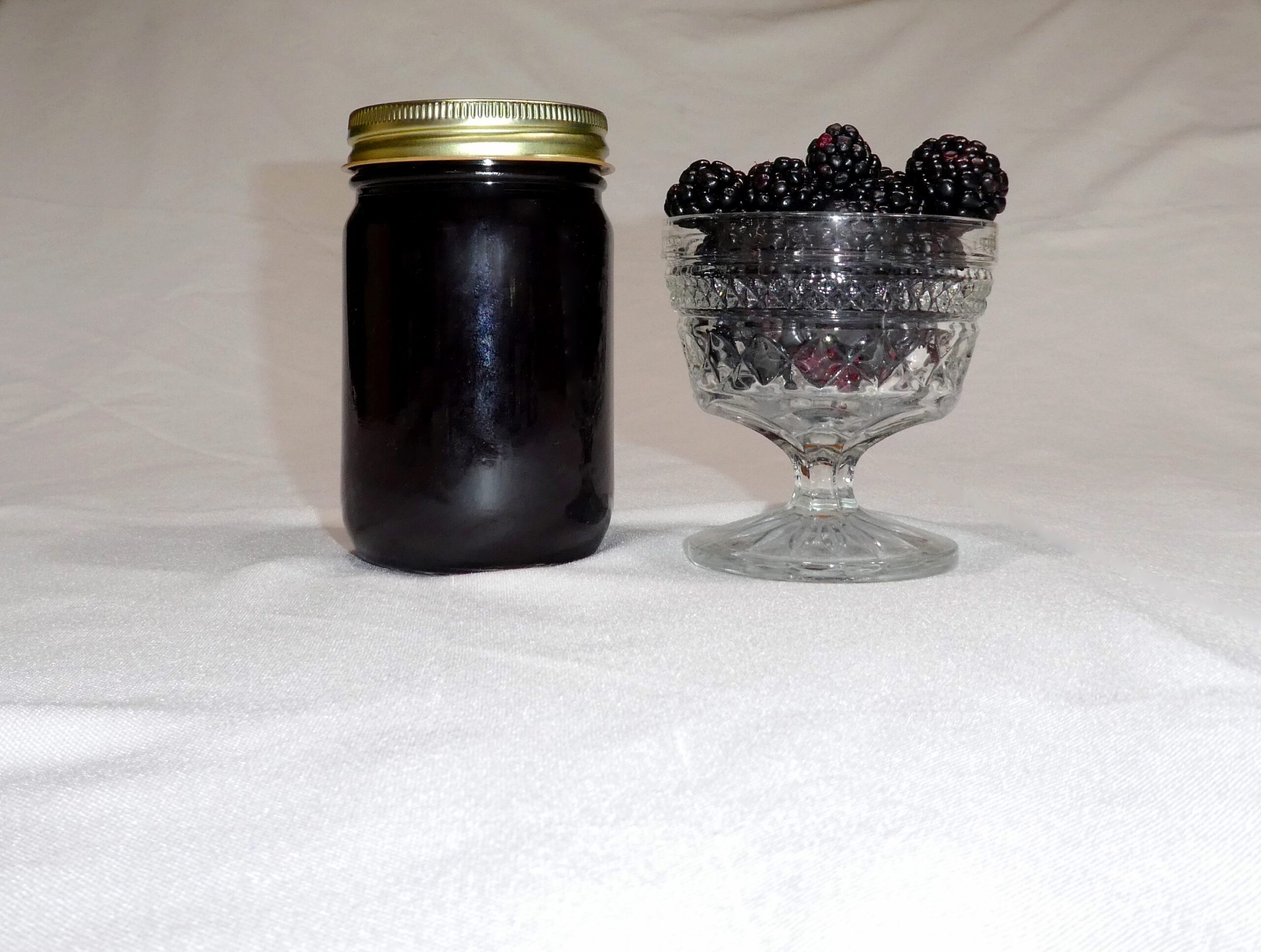 12 oz jar of Blackberry Jam surrounded by blackberries