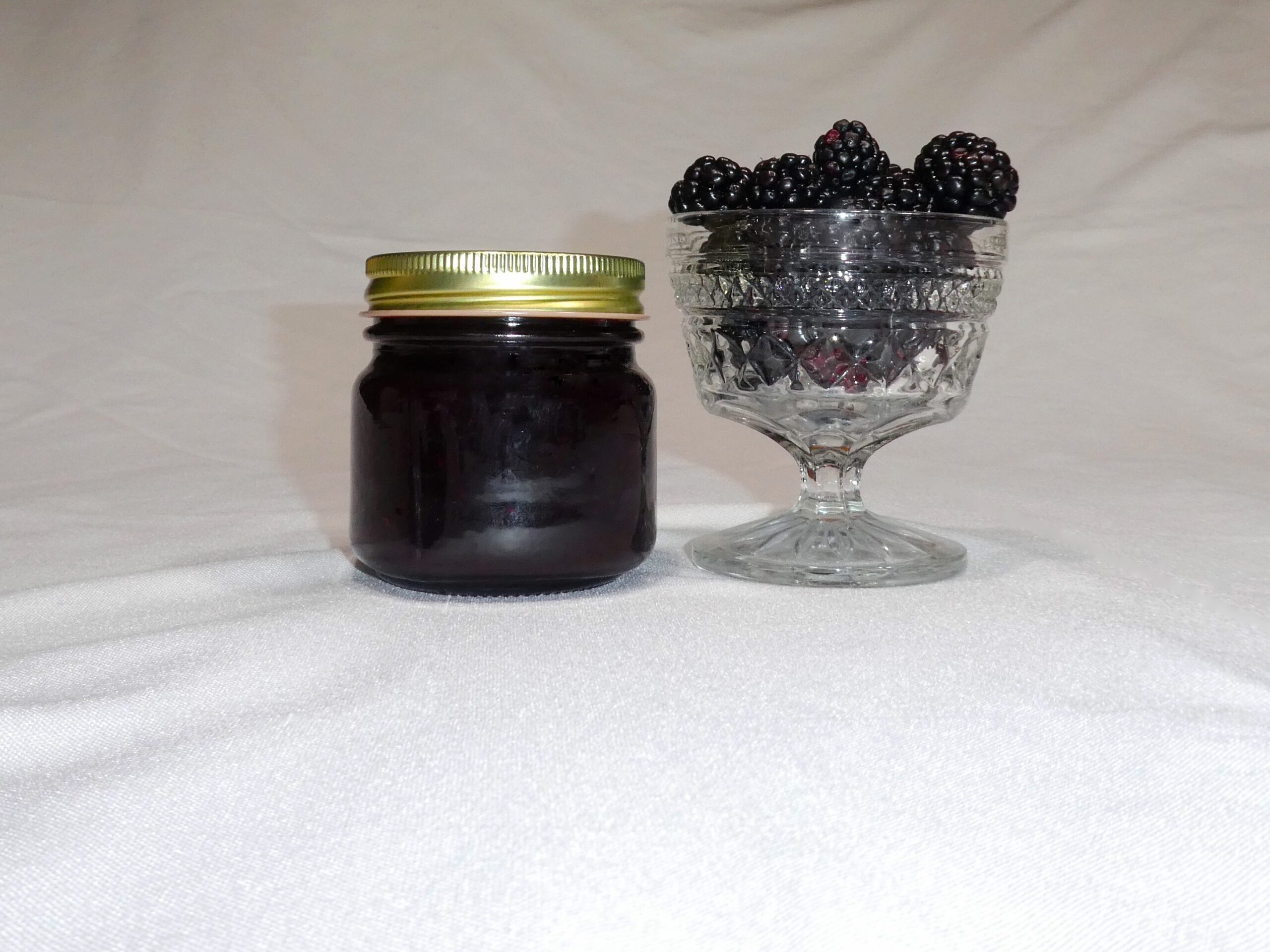 8 oz jar of Blackberry Jam surrounded by blackberries