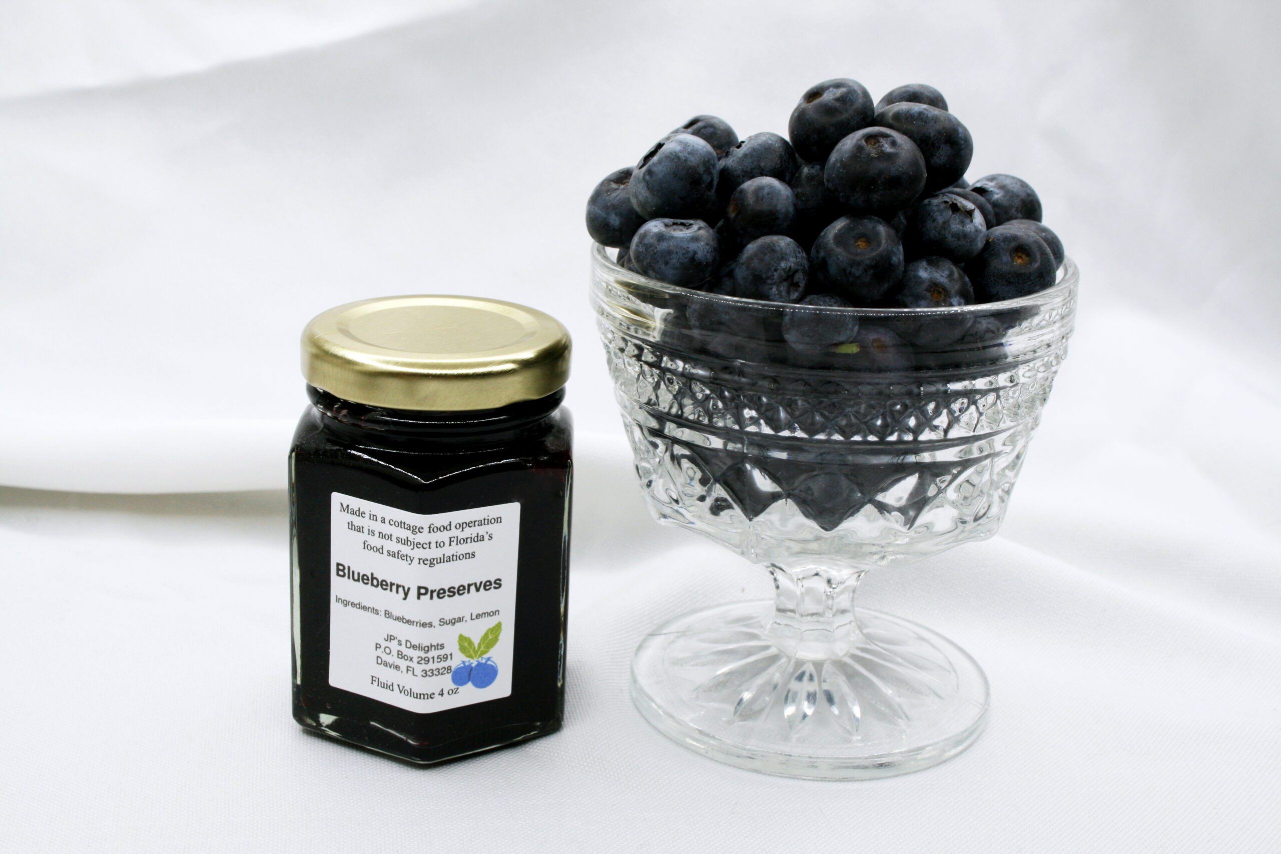4 oz jar of Blueberry Preserves surrounded by blueberries