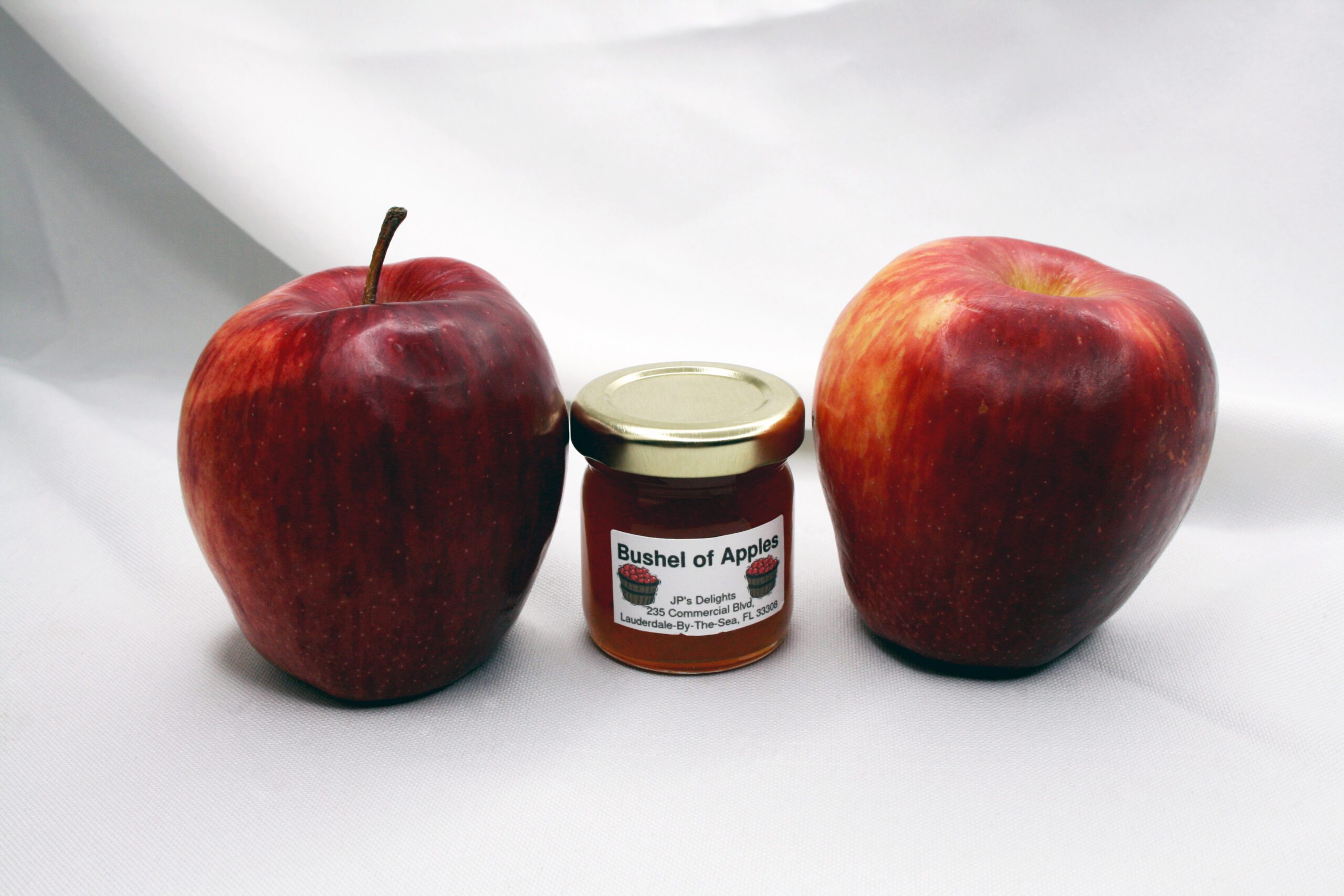 1.5 oz jar of Bushel of Apples Jelly surrounded by its ingredients