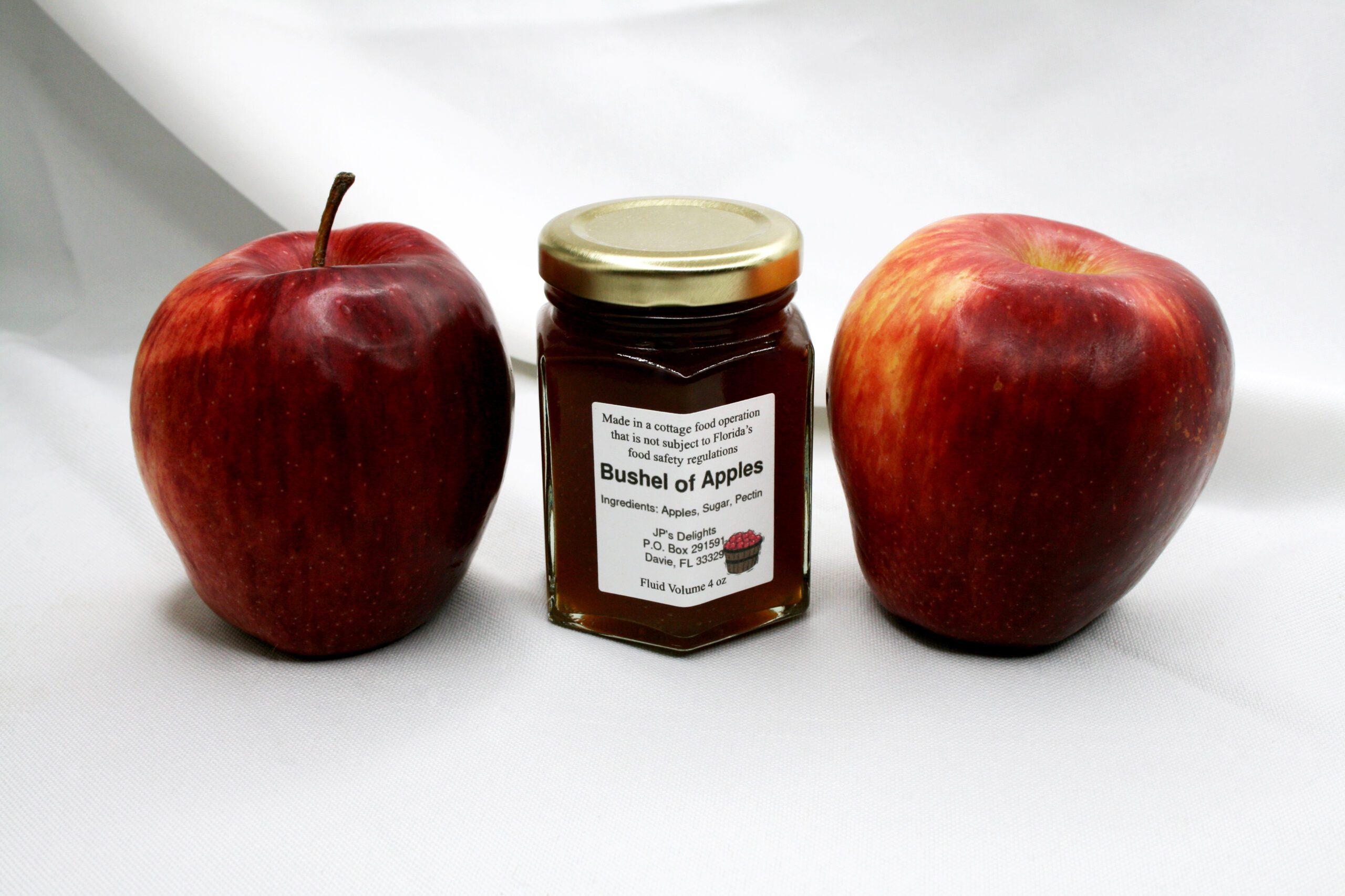 4 oz jar of Bushel of Apples Jelly surrounded by its ingredients