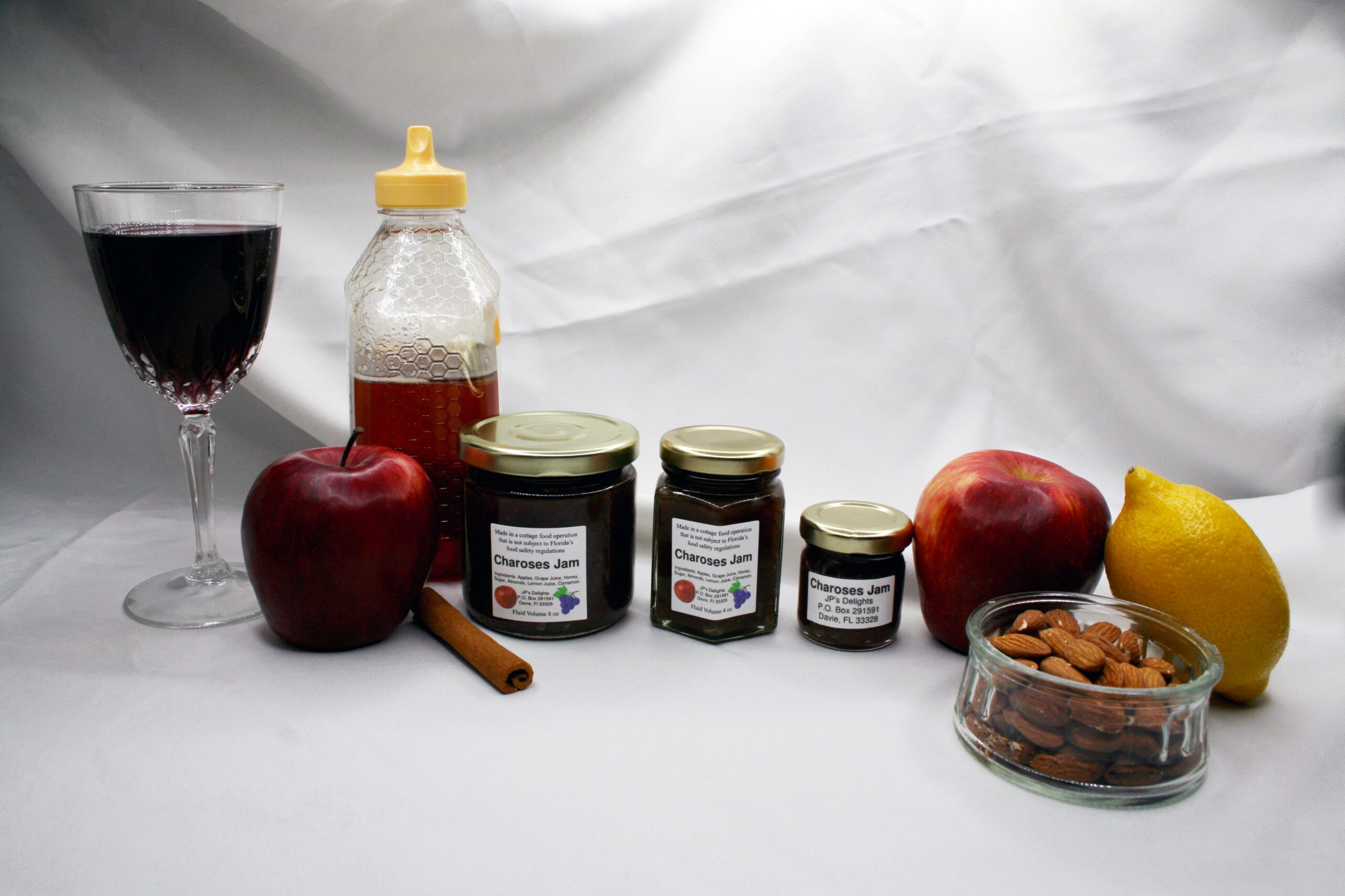 All size jars of Charoses Jam surrounded by its ingredients