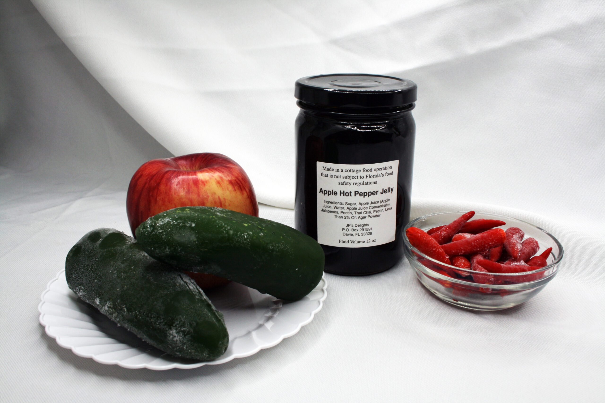 12 oz jar of Apple Hot Pepper Jelly surrounded by its ingredients