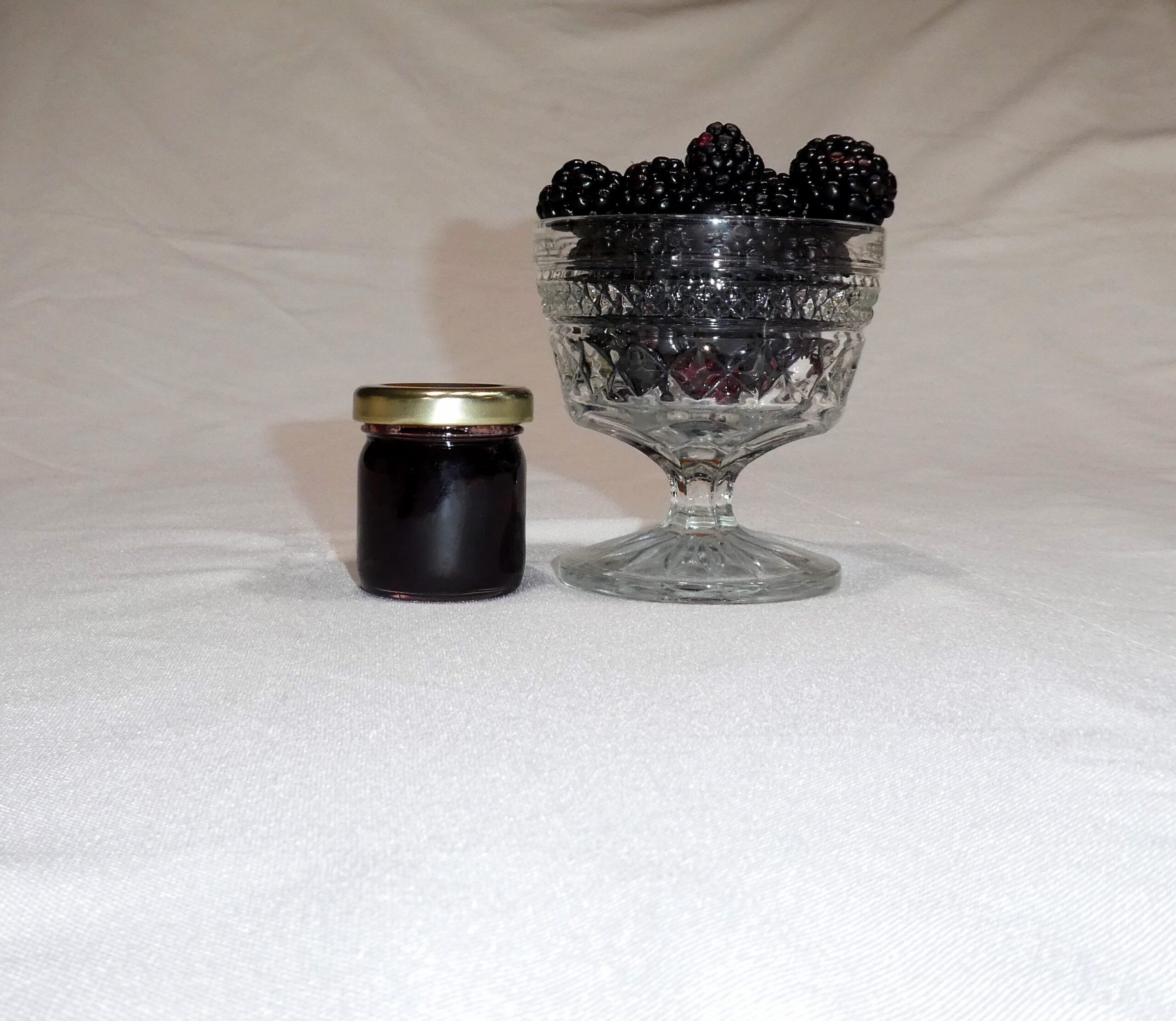 1.5 oz jar of Blackberry Jam surrounded by blackberries
