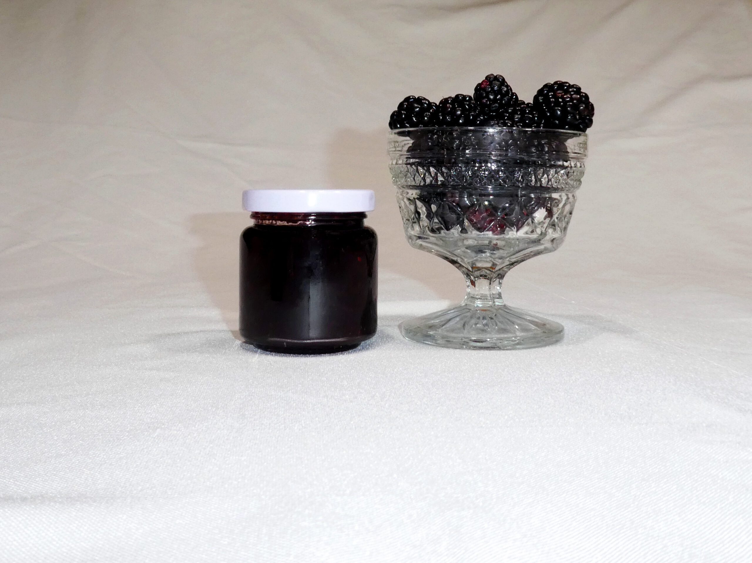 4 oz jar of Blackberry Jam surrounded by blackberries