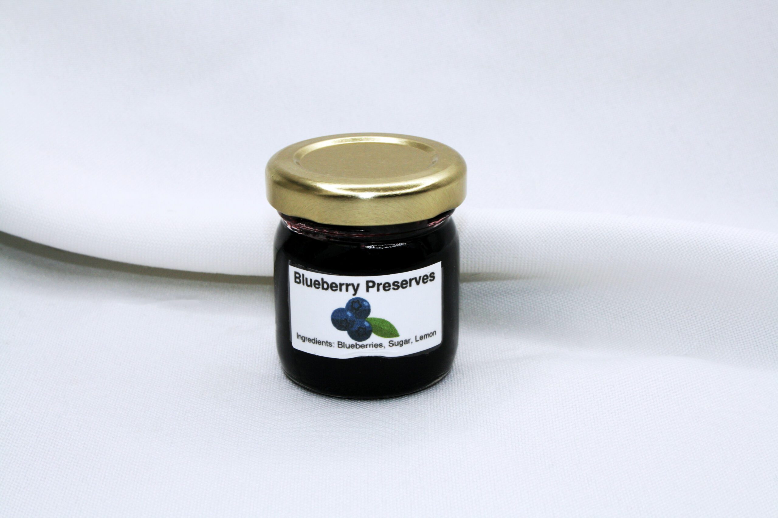 1.5 oz jar of Blueberry Preserves surrounded by blueberries