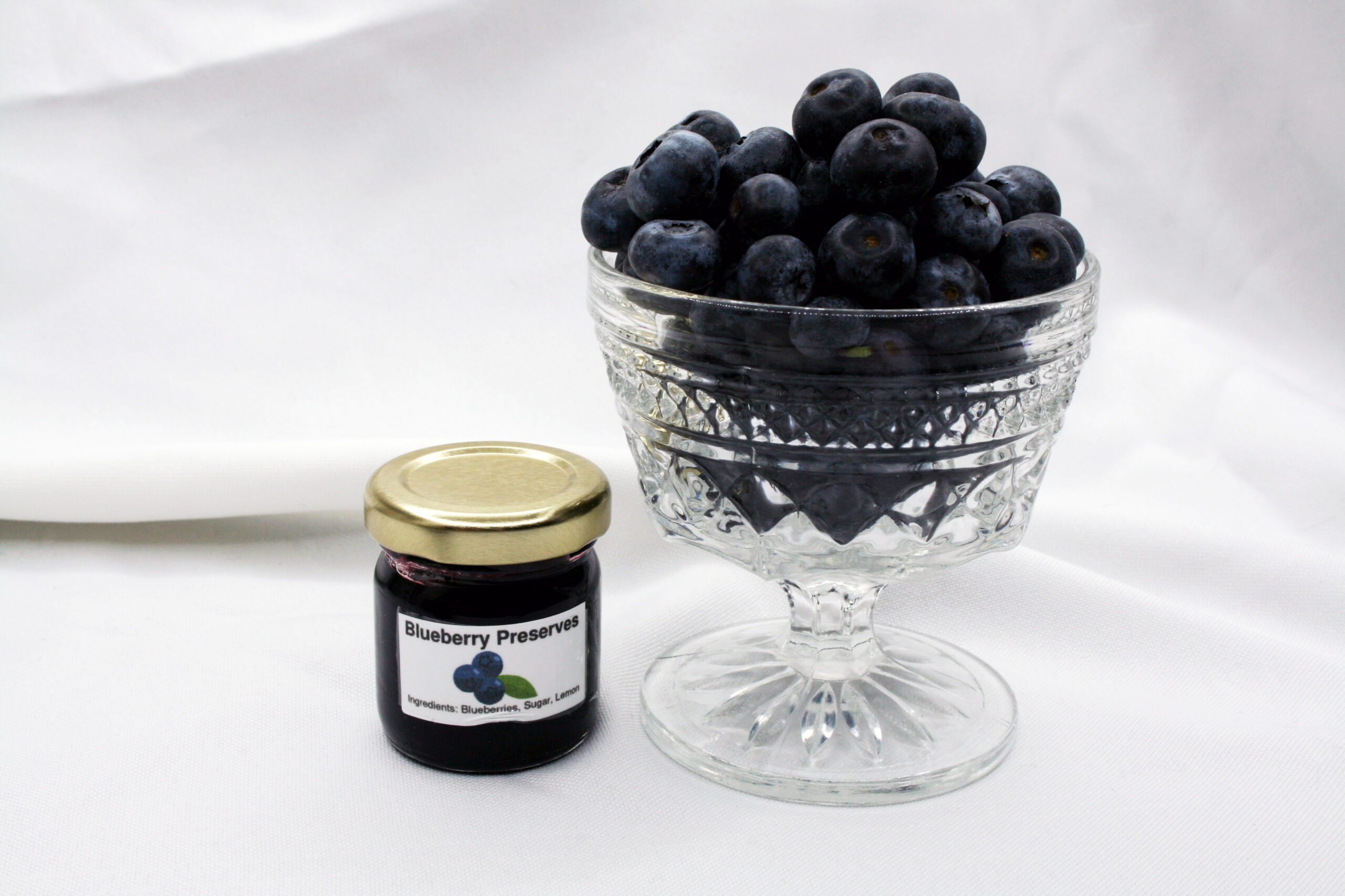 1.5 oz jar of Blueberry Preserves surrounded by blueberries