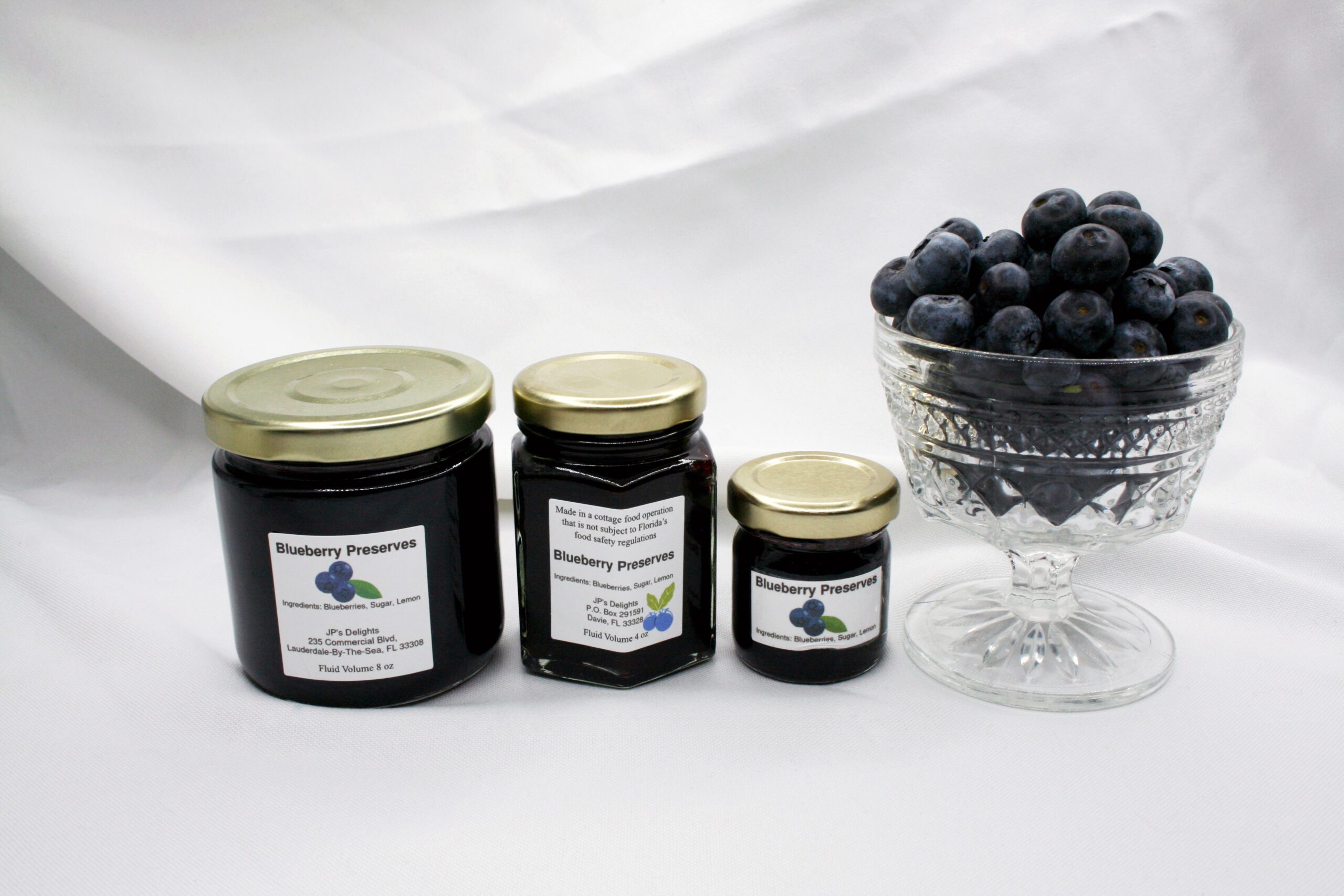 All size jars of Blueberry Preserves surrounded by blueberries