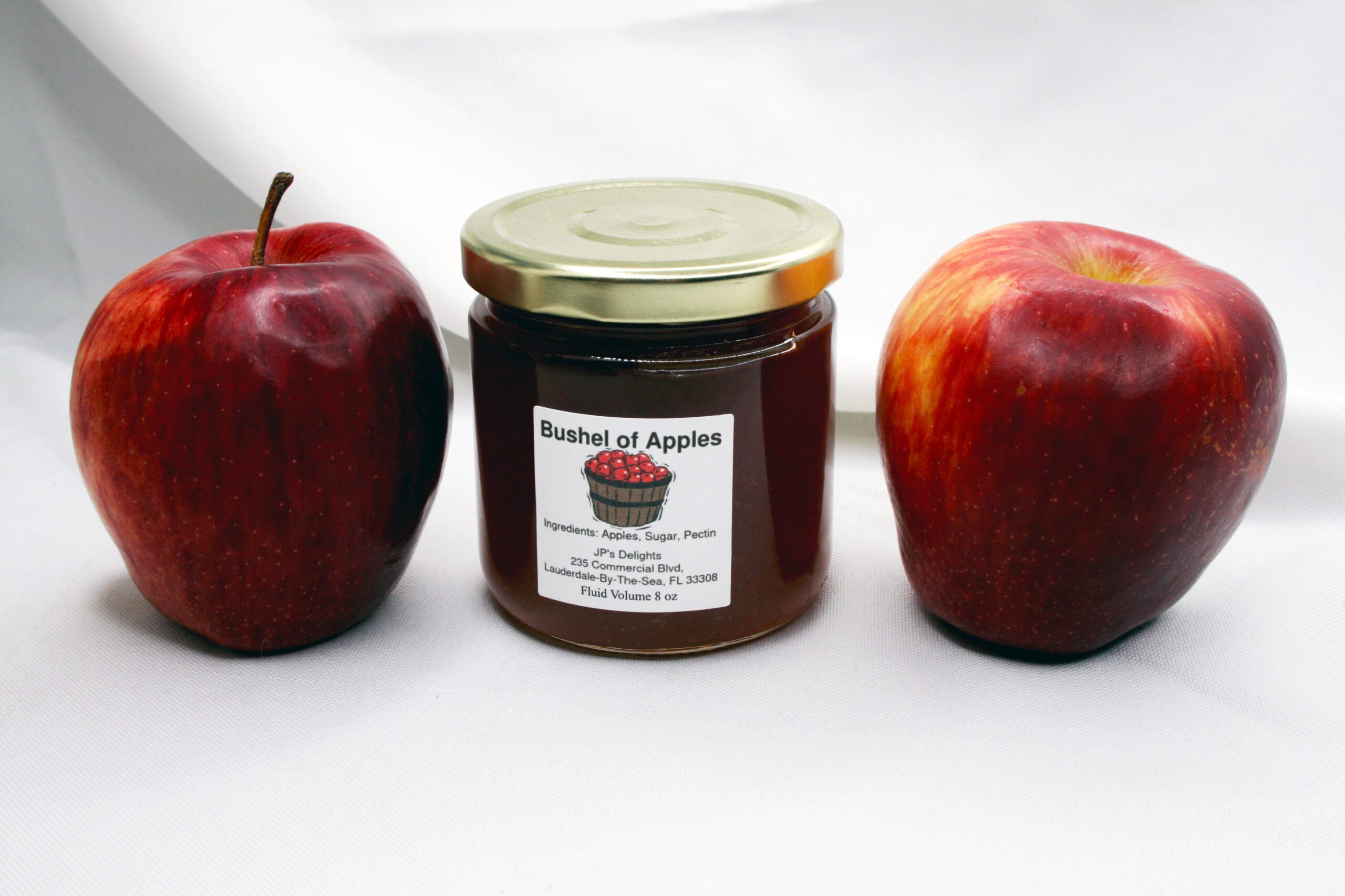 8 oz jar of Bushel of Apples Jelly surrounded by its ingredients