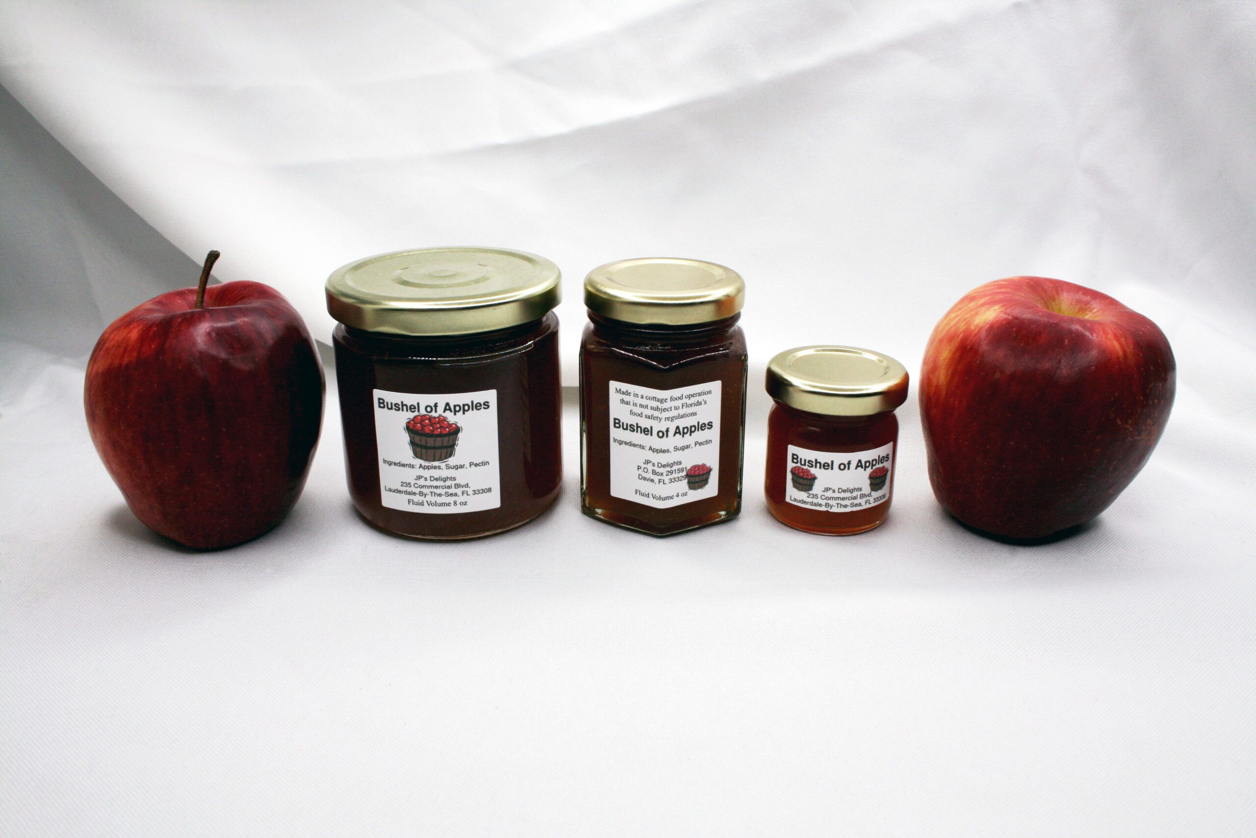 All size jars of Bushel of Apples Jelly surrounded by its ingredients