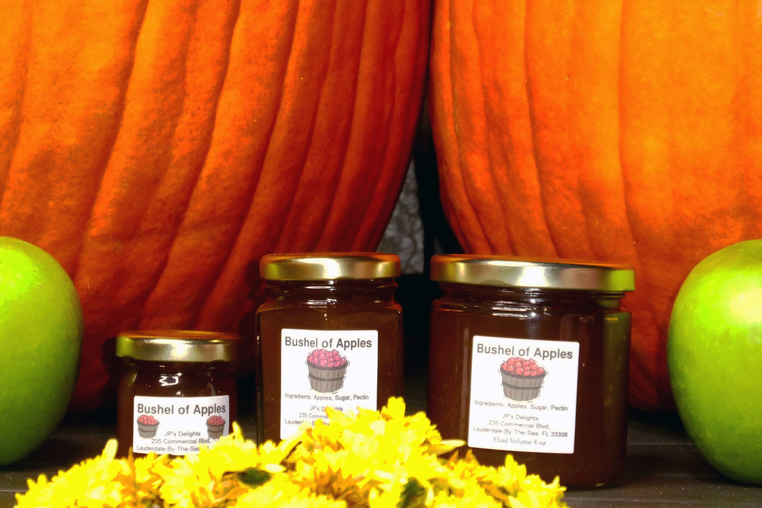 All size jars of Bushel of Apples Jelly set in a closeup of fall background