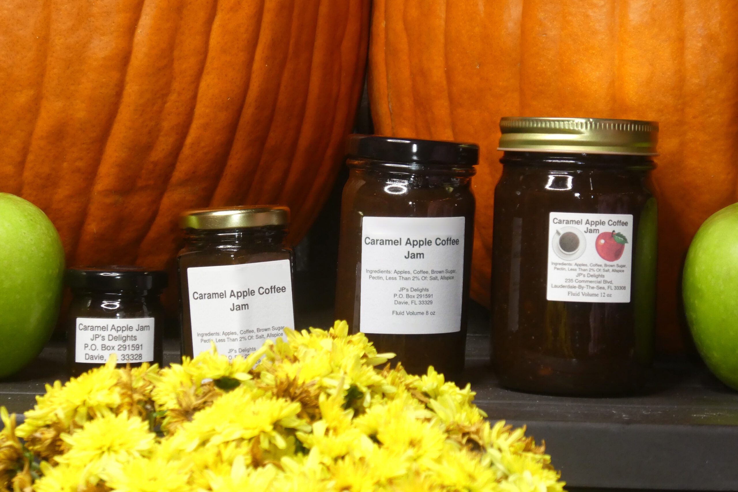 All size jars of Caramel Apple Coffee Jam set in a fall background close up